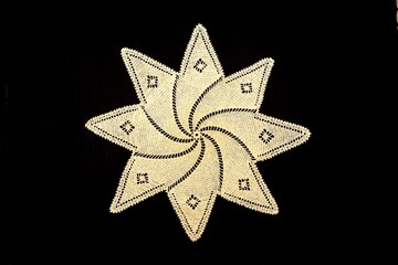 Vintage handmade white knitted napkin isolated on a black background.