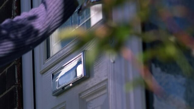 Woman knocking on front door of home