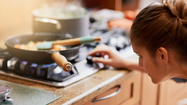 Cooking, kitchen and woman light gas stove in home for healthy diet, nutrition and meal preparation for eating food. Chef, pan and girl at cooker for lunch, dinner and turn on appliance in house