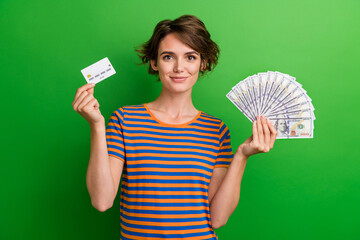 Photo portrait of attractive young woman hold credit card money fan dressed stylish striped clothes isolated on green color background