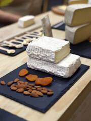 bodegón de queso de cabra camembert con frutos secos sobre una tabla de pizarra en la mesa de la cocina