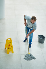 Man, janitor and mopping office for cleaning job or hygiene with caution sign with water, soap or...