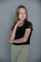 Pensive child with a gentle touch to her face, looking afar. Reflects the depth of young minds and their silent thoughts.