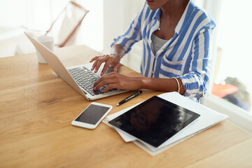 Woman, laptop and paperwork for work from home for blog, social media and email in at desk. African female journalist, typing and research for networking, newspaper article and online magazine