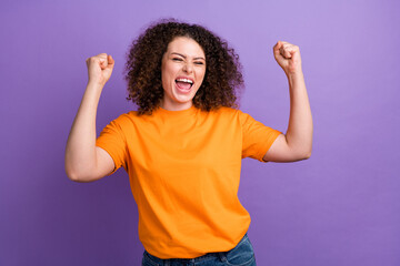 Photo of dreamy excited lady dressed orange t-shirt shouting yes rising fists isolated violet color...