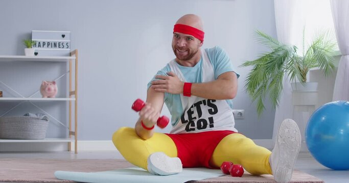 Funny sports man sits and flexes his biceps dedication to healthy lifestyle and strength training of biceps. With each repetition he strengthens his biceps effectiveness of consistent gym workouts