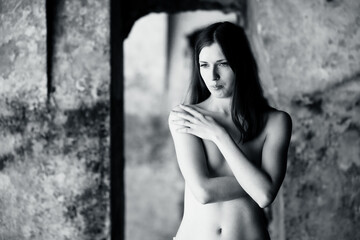 Fototapeta na wymiar Sensual woman undressing in an abandoned building, dramatic portrait