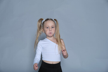 Focused child in dance attire, with her hair tied in playful pigtails, capturing a moment of...
