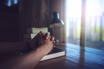 hands praying to god on bible on a wooden table in the morning. Pray for god blessing to wish to have a better life and life to be out of the crisis. begging for forgiveness and believing in goodness.