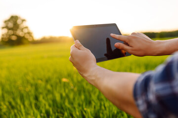 Digital tablet in the hands of a young farmer. Modern digital technologies. Agronomist at the farm. Business Farm.