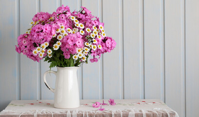 pink phlox and daisies in a bouquet on a table with a lace tablecloth, garden flowers.