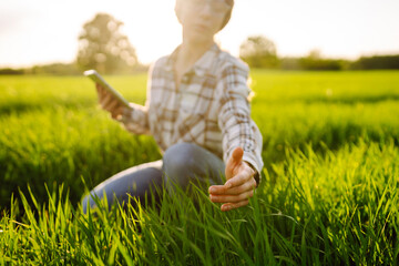 Young female farmer in green field with tablet. Modern digital technologies. Agronomist at the farm. Business Farm.