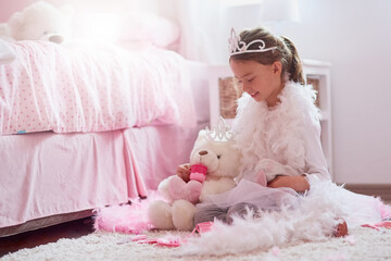 Child, princess and tea party with teddy bear in home with tiara for imagination games, happiness or development. Girl, kid and play with feather costume in bedroom with toys, fancy dress or fantasy © peopleimages.com