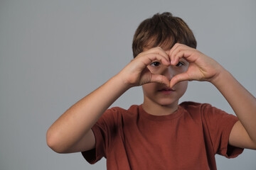Child shows a heart sign, cheerful and loving. Captures the open-heartedness of youth and the...
