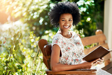 African woman, happy and book on park bench in portrait to relax on vacation with story, language...