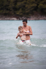Fototapeta premium Mother and son are playing in the sea water