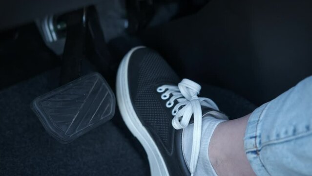 Step on the vehicle pedals. A woman use the auto pedal in the cabin to control the driving.