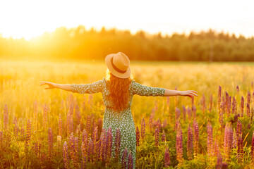 Beautiful woman holding bouquet of lavender flowers walking in summer meadow. Fashion, beauty,...