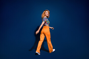 Full body rear profile portrait of nice young lady walk empty space wear top isolated on dark blue color background