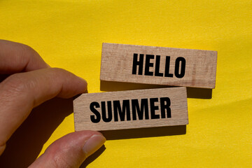 Hello summer words written on wooden blocks with yellow background. Conceptual hello summer symbol....