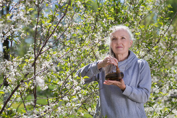 elderly woman with a singing bowl in a flowering garden. Meditation