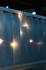 Decorative garland hanging on the fence in the evening. Christmas lights.