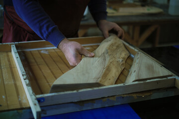The craftsman's hands guide wood into a resin frame, an intricate part of the design process. It's...