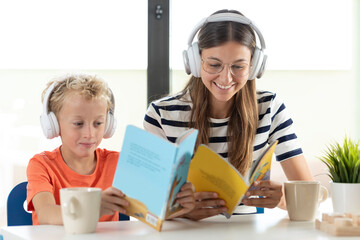 A mother and her son real childrens's books, while listening to music with their white headphones