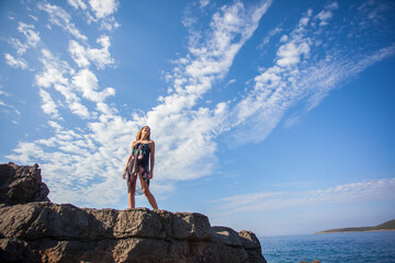 Beautiful young adult standing on the rocky beach