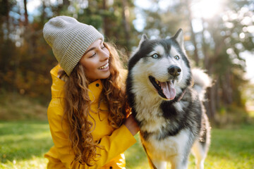 A young woman walks with her dog in the autumn forest. Husky dog.  Pet owner enjoys walking her dog outdoors.