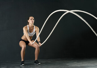 Woman, studio and training with battle rope for fitness, calorie and body workout for vitality or...