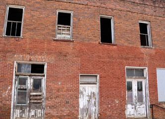 Photo of old window on old building. Shot in historic downtown Acworth Georgia. Red brick building with several windows. Rustic, old building with white doors and rotting wood windows