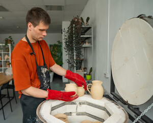 Caucasian man loading ceramic products into a special kiln. 