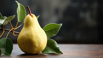 Yellow pear on a wooden table with green foliage. The background is dark, with a blurry image of the wall.