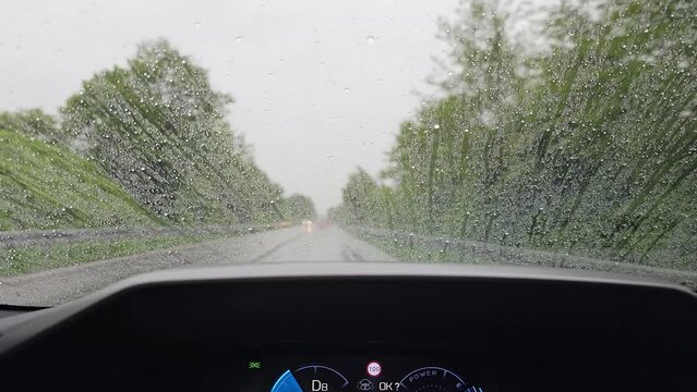 Auto f&auml;hrt auf der Landstra&szlig;e bei Regen mit einer Scheibenversiegelung, der Regen perlt w&auml;hrend der F
fahrt ab