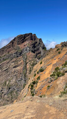 A striking view of Madeira’s rugged orange cliffs and towering mountain peaks under a clear blue sky