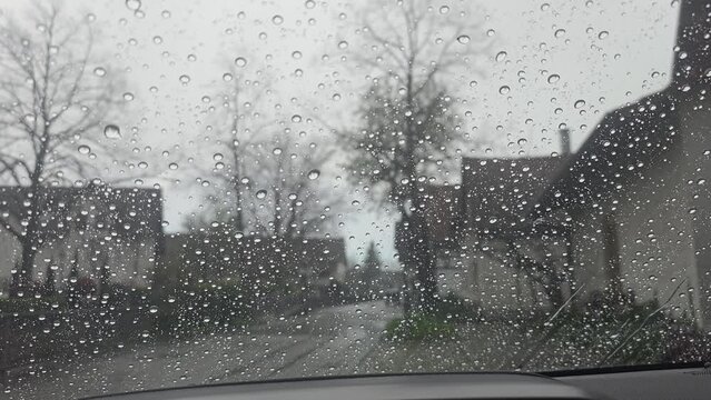 Window with window seal on a vehicle in the city center during a rain shower, vehicles drive past the rain beads up