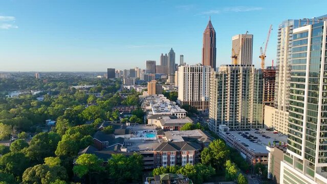 4K drone footage flying over trees and buildings towards Atlanta's skyline.  Footage near Midtown Atlanta.  Smooth drone video displaying green tree tops and sprawling skyscrapers