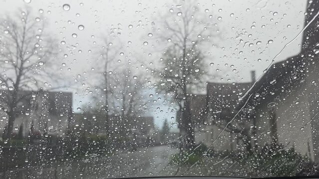 Window with window seal on a vehicle in the city center during a rain shower, vehicles drive past the rain beads up