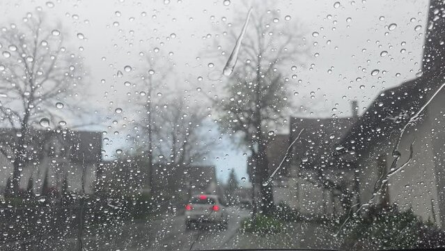 Window with window seal on a vehicle in the city center during a rain shower, vehicles drive past the rain beads up