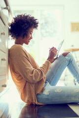 Woman, tablet and home on floor for relax, networking and social media news or browsing on web for...
