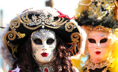 masked women with covered faces and hats with colorful wigs in Venice during the Carnival