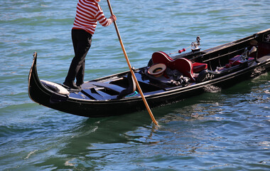 Gondolier on the Gondola Boat while rowind in the Grand Canal in Venice with jersey red and white