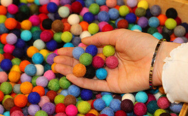 many colorful balls made of boiled wool on sale in the hand of girl  ideal for making personalized...