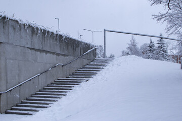 Snowy staircase and a concrete wall in winter city urban environment with copy space