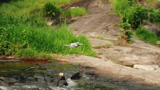 Drone flies over river capturing rich plants, flowing water. Aerial glides above natural landscapes, riverbanks, woods. Outdoor enthusiasts, filmmakers value river flyover, exploring wilderness sky.
