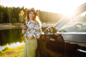 Happy young woman driver traveler using smartphone during travel. Travel, weekend concept.