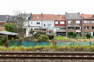 Asse, Flemish Brabant, Belgium - 09 24 2021: Railway tracks and traditional backyards
