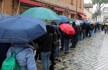 line of people waiting their turn with umbrellas in the rain
