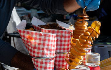 Obraz premium Fried sweet potatoes chips, spirals on skewers on Portobello road food market, London, UK